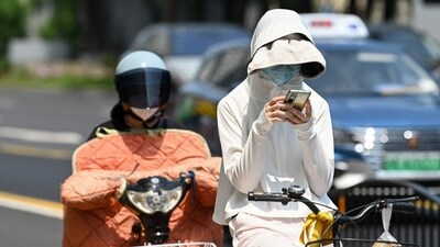 A woman wearing sun protective clothing commutes on a bicycle amid hot weather in Shanghai on May 29, 2023. (AFP) A woman wearing sun protective clothing commutes on a bicycle amid hot weather in Shanghai on May 29, 2023. (AFP)