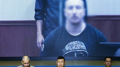 Thailand's National Police Chief Damrongsak Kittiprapas speaks during a press conference on receiving Canadian contract killer Matthew Dupre, extradited from Canada to Thailand on a charge of murdering Canadian gangster Jimi "Slice" Sandhu in Phuket, as his image appears on a screen, in Bangkok. (Reuters)