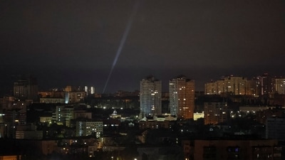 Ukrainian servicemen use a searchlight as they search for drones in the sky over the city during a Russian drone and missile strike. (REUTERS)