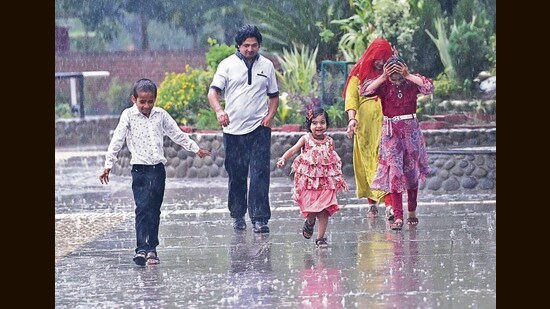A family caught in the rain at Sukhna Lake in Chandigarh on Monday. (Keshav Singh/HT)