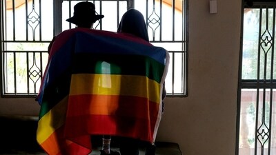 A gay Ugandan couple cover themselves with a pride flag as they pose for a photograph in Uganda on March 25, 2023. (AP Photo, File) A gay Ugandan couple cover themselves with a pride flag as they pose for a photograph in Uganda on March 25, 2023. (AP Photo, File)