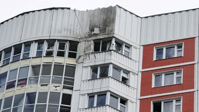 A woman looks out of a window of a damaged multi-storey apartment block following a reported drone attack in Moscow, Russia. (REUTERS)