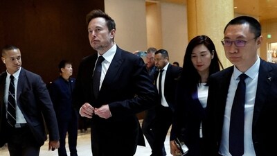 Tesla chief executive officer Elon Musk walks next to Tesla's Senior Vice President Tom Zhu and Vice President Grace Tao as he leaves a hotel in Beijing, China (REUTERS)