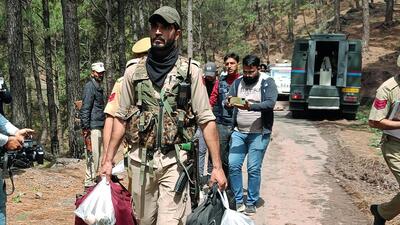 A police personnel carrying arms, ammunition, and other material recovered from a terrorist who was killed in Dassal Rajouri encounter, on Friday. (ANI)