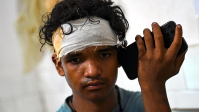 A wounded survivor rescued from a carriage wreckage of a three-train collision near Balasore, speaks on a phone at the Soro government hospital in Odisha, on Saturday. (AFP) A wounded survivor rescued from a carriage wreckage of a three-train collision near Balasore, speaks on a phone at the Soro government hospital in Odisha, on Saturday. (AFP)