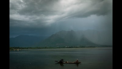 Kashmiri fishermen row their shikara, or traditional gondola, on the Dal Lake on their way home as it rains in Srinagar. (AP)