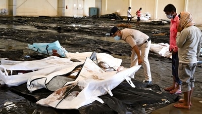 A policeman helps a man to identify his family member's body at a business park used as temporary mortuary for the dead recovered from the carriage wreckage of the three-train collision. (AFP) A policeman helps a man to identify his family member's body at a business park used as temporary mortuary for the dead recovered from the carriage wreckage of the three-train collision. (AFP)