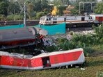 A train moves past damaged coaches, after the tracks were restored, at the site of a train collision.