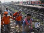 Workers walk on a rail track as a train arrives at Bahanaga Bazar railway station.