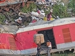 Porters carry goods collected from the mangled coaches at the triple train mishap site.