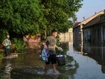 Local residents carry their belongings from a flooded house after the Nova Kakhovka dam breached, amid Russia's attack on Ukraine.