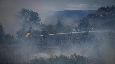 A firefighter directs water on a grass fire on an acreage behind a residential property in Kamloops, British Columbia, Canada. (AP) A firefighter directs water on a grass fire on an acreage behind a residential property in Kamloops, British Columbia, Canada. (AP)