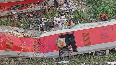 Porters carry goods collected from the mangled coaches at the triple train mishap site. (PTI)