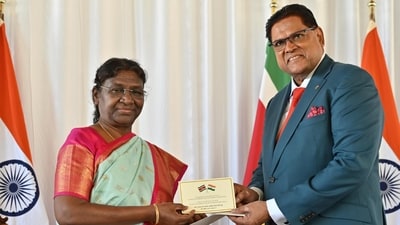 President Droupadi Murmu being presented special covers of stamps to mark 150 years of arrival of Indians in Suriname by President of Suriname Chan Santokhi, in Suriname, Monday. (PTI)
