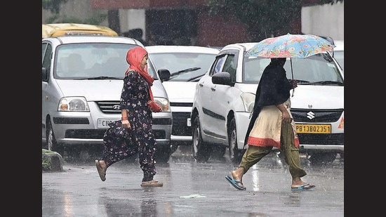 Pedestrians caught in the rain at the Sector 33/45 dividing road in Chandigarh. (Keshav Singh/HT)