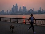 A woman jogs with a dog along the Hudson River shortly after sunrise, as haze and smoke caused by wildfires in Canada hang over the Manhattan skyline, in New York, on June 7. Environment Canada, the government-run weather agency told Reuters that wildfire smoke can harm health even at low concentrations, and people with lung or heart diseases, as well as older adults, children, and pregnant women, were at higher health risk from wildfire smoke,