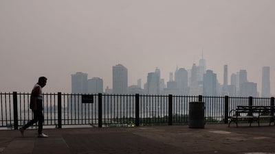 A pedestrian walks along the Brooklyn Promenade as a reddish haze enshrouds the Manhattan skyline as a result of Canadian wildfires on June 6, There are blazes in nearly all of Canada's 10 provinces and territories, with Quebec being the worst impacted due to multiple fires caused by lightning, reported Reuters.&nbsp; (Spencer Platt/ Getty Images via AFP)