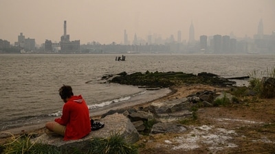 A man sits in front of the New York city skyline and east river shrouded in smoke, in Brooklyn, on June 6.&nbsp; (Ed Jones / AFP)