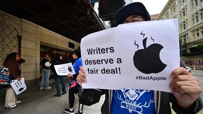 Justin S. Lee, a writer and director in TV and Film, holds a sign in front of Apple's flagship store during the writer-led Apple Day of Action, during the continuing strike by the Writers Guild of America (WGA), in Los Angeles, California, on June 5, 2023. The Apple Day of Action is calling on Apple to come back to the table and help end the strike. Picketing writers say they are striking for better compensation in a field that has been disrupted by the streaming industry. Writers also say they are looking for more stable working conditions and a better share of the profits generated by the rise of streaming. (Photo by Frederic J. BROWN / AFP) (AFP) Justin S. Lee, a writer and director in TV and Film, holds a sign in front of Apple's flagship store during the writer-led Apple Day of Action, during the continuing strike by the Writers Guild of America (WGA), in Los Angeles, California, on June 5, 2023. The Apple Day of Action is calling on Apple to come back to the table and help end the strike. Picketing writers say they are striking for better compensation in a field that has been disrupted by the streaming industry. Writers also say they are looking for more stable working conditions and a better share of the profits generated by the rise of streaming. (Photo by Frederic J. BROWN / AFP) (AFP)