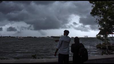 People enjoy weather as dark clouds cover the city skyline during the onset of monsoon over Kerala a week later than usual, in Kochi, on Thursday. (PTI)