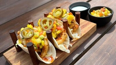 3. Prawn and Mango tacos by Chef Agnibh Mudi: Ingredients&nbsp;- Soft mini tortilla 3 pcs, Fresh prawns 8-12pcs, Paprika 2gm, Olive oil 10ml. Ingredients for Mango salsa - Fresh mango 100gm, Onion 15gm, Tomato 15gm, Mint 3gm, Red chilli 2gm, Sour cream 15gm, Jalapeno pepper 5gm, Fresh coriander sprigs. Ingredients for garnish&nbsp;- Chilli oil.&nbsp;Method - Warm the tacos on a pan or in oven. Pan toss the prawns in olive oil with garlic, parika and season it with salt and pepper.&nbsp;For the salsa mix all the ingredients in a bowl. Season it with salt and pepper and keep it chilled.&nbsp;Assemble the tacos with fresh lettuce (preferably iceberg). Place the cooked prawns on the iceberg. Top it up with a full spoon of the mango salsa. Put sour cream and jalapeno pepper slices on top of that. Garnish the tacos with fresh coriander sprig and chilli oil.&nbsp; ( Chef Agnibh Mudi)