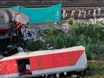 Policemen walk on rail tracks near damaged coaches at the site of a train collision following the accident in Balasore district in the eastern state of Odisha, 