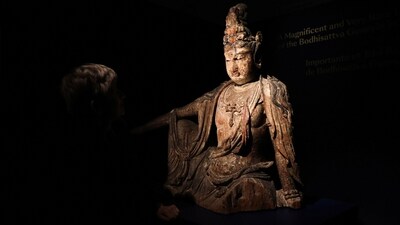 Head of Chinese Art Caroline Schulten at Bonhams auction house looks at a rare Buddha statue, believed to be from the 12th century in China, before its auction in Paris, (Reuters)