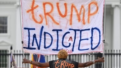 A woman celebrating the indictment of former US president Donald Trump holds a banner in front of the White House. (AFP) A woman celebrating the indictment of former US president Donald Trump holds a banner in front of the White House. (AFP)