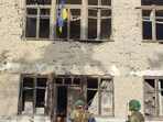 Ukrainian soldiers stand in front of a building with a Ukrainian flag on it, during an operation that claims to liberate the first village amid a counter-offensive, in a location given as Blahodatne, Donetsk Region, Ukraine.