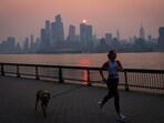 A woman jogs with a dog along the Hudson River shortly after sunrise, as haze and smoke caused by wildfires in Canada. A woman jogs with a dog along the Hudson River shortly after sunrise, as haze and smoke caused by wildfires in Canada.