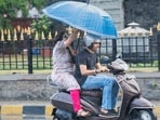Pillion passenger deals with sudden shower of rain at Chhatrapati Shivaji Maharaj Terminus, in Mumbai. (Photo by Anshuman Poyrekar/ Hindustan Times)