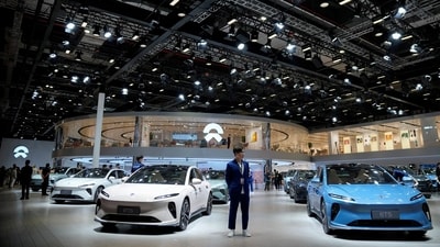 A staff member stands near Nio ET5 cars at its booth at the Auto Shanghai show, in Shanghai, China, (REUTERS)