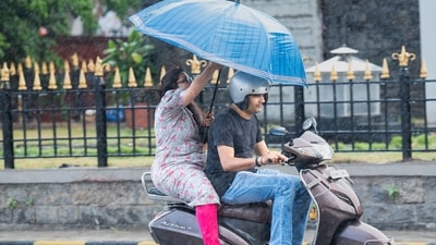 Pillion passenger deals with sudden shower of rain at Chhatrapati Shivaji Maharaj Terminus, in Mumbai. (Photo by Anshuman Poyrekar/ Hindustan Times) Pillion passenger deals with sudden shower of rain at Chhatrapati Shivaji Maharaj Terminus, in Mumbai. (Photo by Anshuman Poyrekar/ Hindustan Times)
