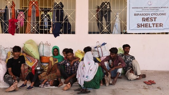 People evacuated from Kandla port sit outside a school converted into a shelter, before the arrival of cyclone Biparjoy, in Gandhidham, Gujarat on June 13. The evacuation process is still underway and so far 21,000 people from different coastal districts have been shifted to temporary shelters, reported PTI.&nbsp;(Francis Mascarenhas / Reuters)