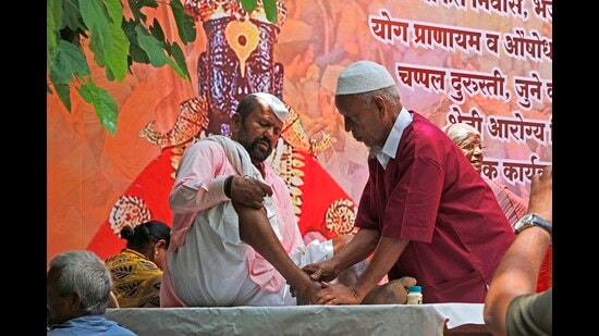 A muslim man offers foot massage to a warkari at Nana peth on Tuesday. (RAVINDRA JOSHI/ HT)