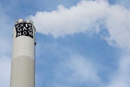 A climate activist attaches a banner to the chimney of a natural gas power plant in Erlangen, Germany. (AP) A climate activist attaches a banner to the chimney of a natural gas power plant in Erlangen, Germany. (AP)