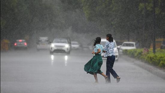 People out in the rain on Jaswant Singh Road in New Delhi on Friday. (Raj K Raj/HT Photo)