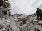 A man stands on debris of a building heavily damaged by a Russian military strike. 