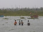 People wade through waist deep water to check on their boats anchored at Jakhau port after landfall of Cyclone Biparjoy at Jakhau in Kutch district of Gujarat, Saturday.(AP)