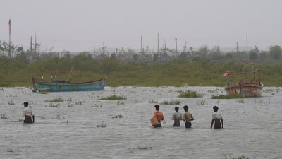 People wade through waist deep water to check on their boats anchored at Jakhau port after landfall of Cyclone Biparjoy at Jakhau in Kutch district of Gujarat, Saturday. (AP) People wade through waist deep water to check on their boats anchored at Jakhau port after landfall of Cyclone Biparjoy at Jakhau in Kutch district of Gujarat, Saturday. (AP)