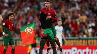 A supporter invades the pitch and grabs Portugal's forward Cristiano Ronaldo during the UEFA Euro 2024 group J qualification football match (AFP)