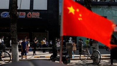 A China's flag flutters near people lining up to get tested at a makeshift nucleic acid testing site. (File image) (REUTERS)