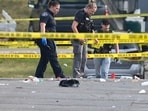 Investigators look over the scene of an overnight mass shooting at a strip mall in Willowbrook, Ill., Sunday, June 18, 2023.