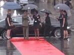 The protocol officer was seen standing outside the vehicle with an umbrella. The protocol officer was seen standing outside the vehicle with an umbrella.