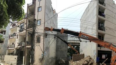 The tilted five-storey building is supported by a crane. (Parveen Kumar/ HT) The tilted five-storey building is supported by a crane. (Parveen Kumar/ HT)