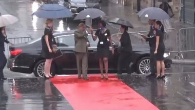 The protocol officer was seen standing outside the vehicle with an umbrella. (Screegrab)