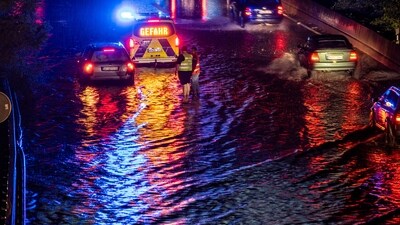 Vehicles drive through a flooded section of the A59 highway as heavy rain falls in Duisburg, Germany. (AP)