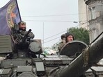 Servicemen sit in a tank with a flag of the Wagner Group military company, as they guard an area at the HQ of the Southern Military District in a street in Rostov-on-Don, Russia.