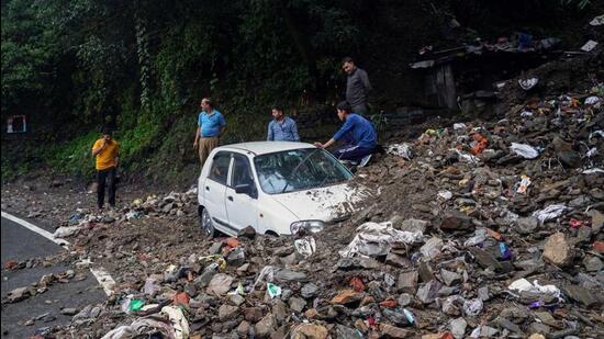 People trying to get a vehicle out of debris after it got buried following heavy rainfall in Shimla on Saturday. (Deepak Sansta/HT)