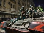 Membes of the Wagner Group military company sit atop of a tank on a street in Rostov-on-Don. 